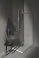 Duschsystem von Ideal Standard mit festem Duschkopf, moderner Wandmontage und gläserner Duschabtrennung. Praktische Ablagefläche aus schwarzem Material neben der Dusche.
